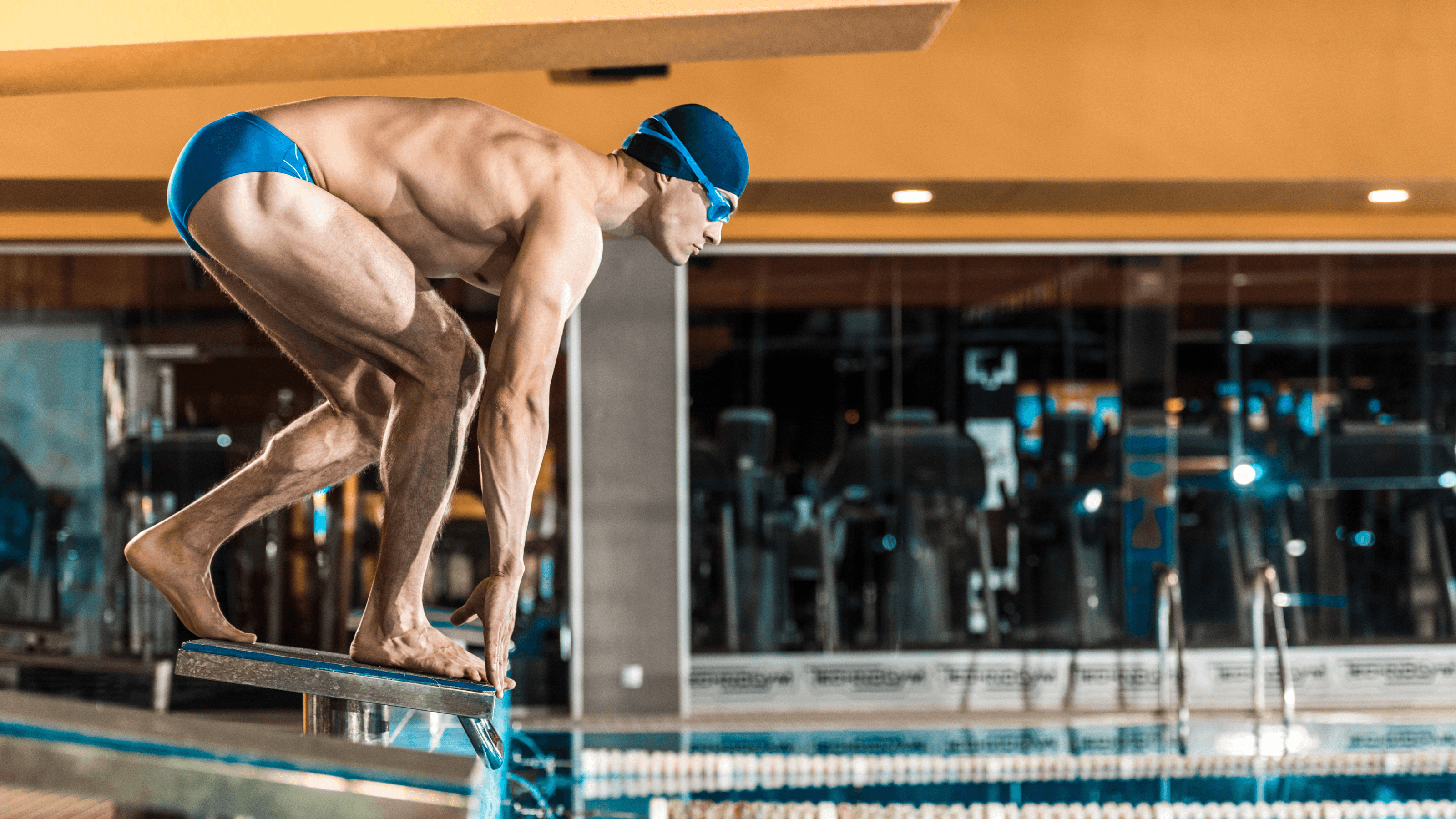 Ein INJOY Mitglied springt vom Startblock in das Schwimmbad des INJOY Gym and Swim Fitnessstudios.