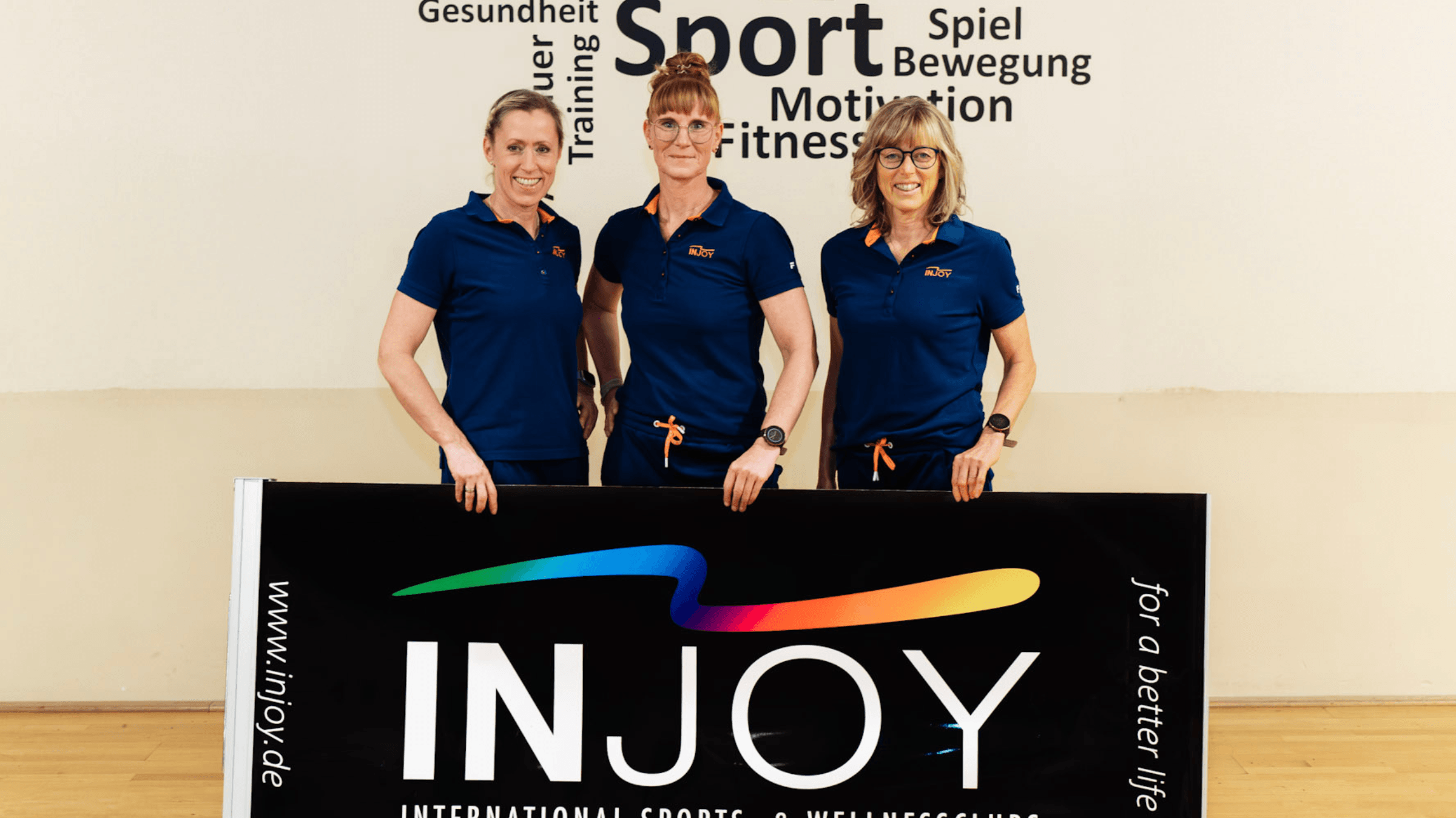 Das Team vom INJOY Fitnessstudio Papenburg posiert vor einem INJOY Banner.