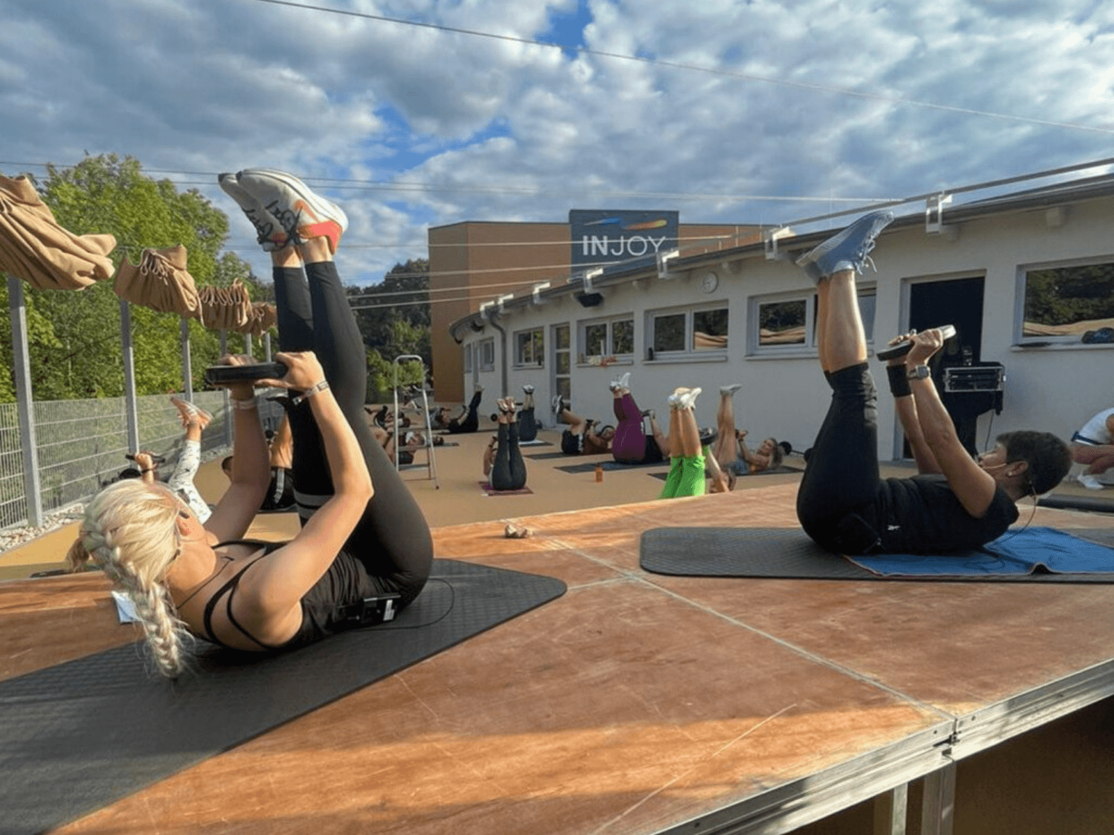 Mehrere Personen üben auf der Outdoor-Trainingsfläche im INJOY Fitnesstudio Rudolstadt eine Bachübung aus.