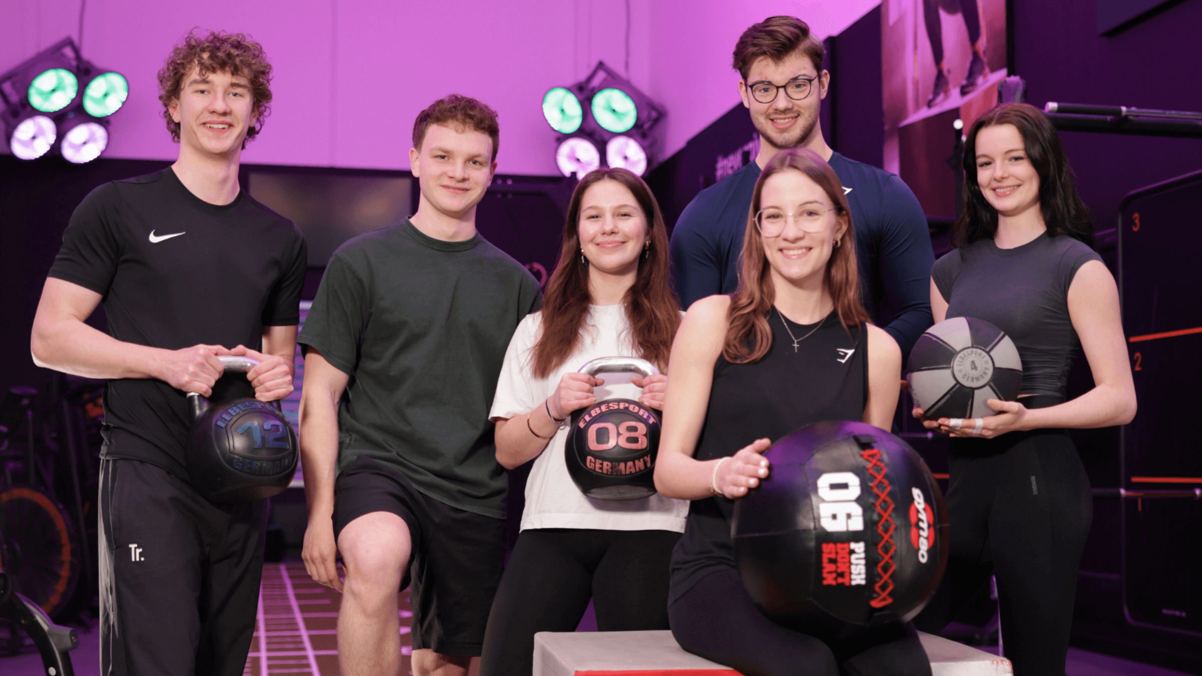 Gruppenbild von sechs Frauen und Männern mit Kettlebells und Bällen in der Hand im INJOY Fitnessstudio Dorsten.