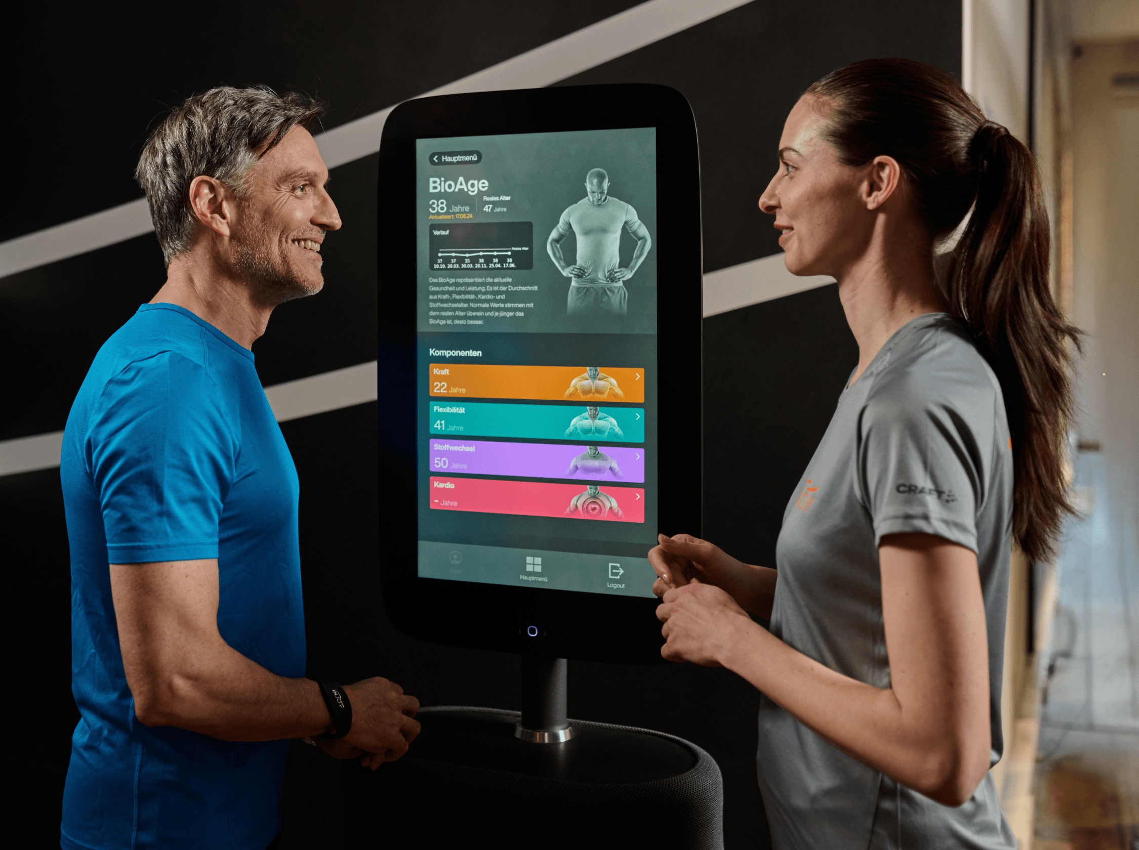 Trainerin bespricht mit einem Mitglied die Ergebnisse eines digitalen Gesundheitschecks und das BioAge im INJOY Fitnessstudio.