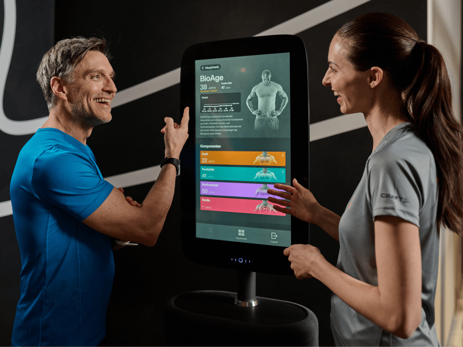 Eine dunkelhaarige INJOY Trainerin macht mit einem Mitglied eine medizinische Fitnessanalyse.