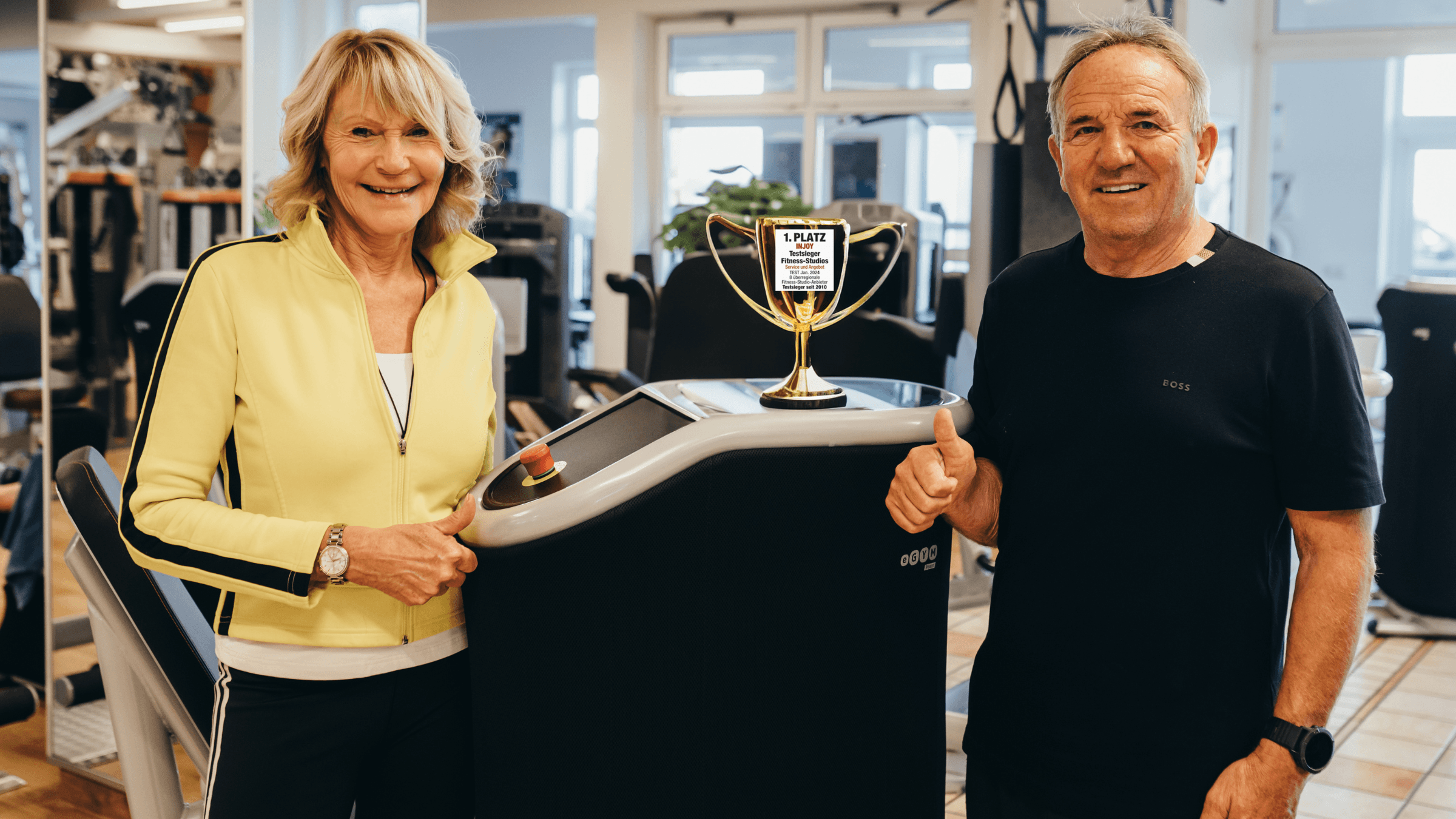Die beiden Geschäftsinhaber des INJOY Fitnessstudios in Waldkraiburg posieren stolz mit der Auszeichnung zum Testsieger-Fitnessstudio.