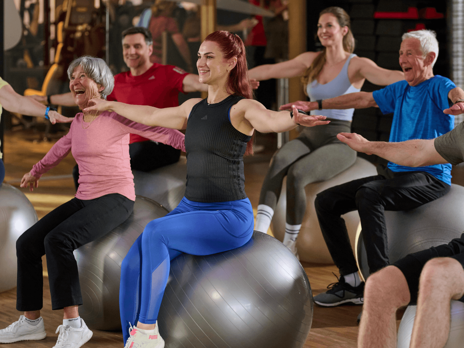 Gruppenkurs-Teilnehmer sitzen auf einem Gymnastikball im INJOY Fitnessstudio Neuötting