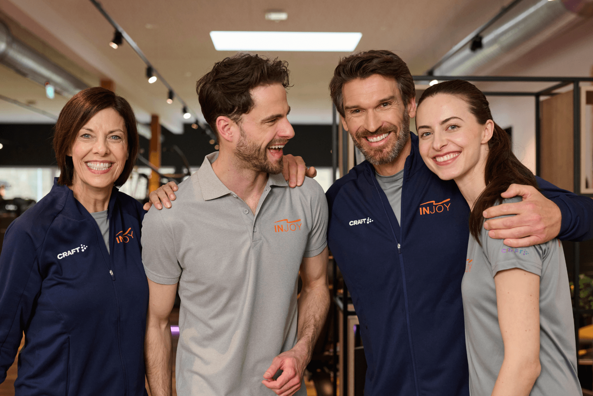 Vier gut gelaunte INJOY Mitarbeiter posieren für ein Gruppenfoto und lachen dabei in die Kamera.