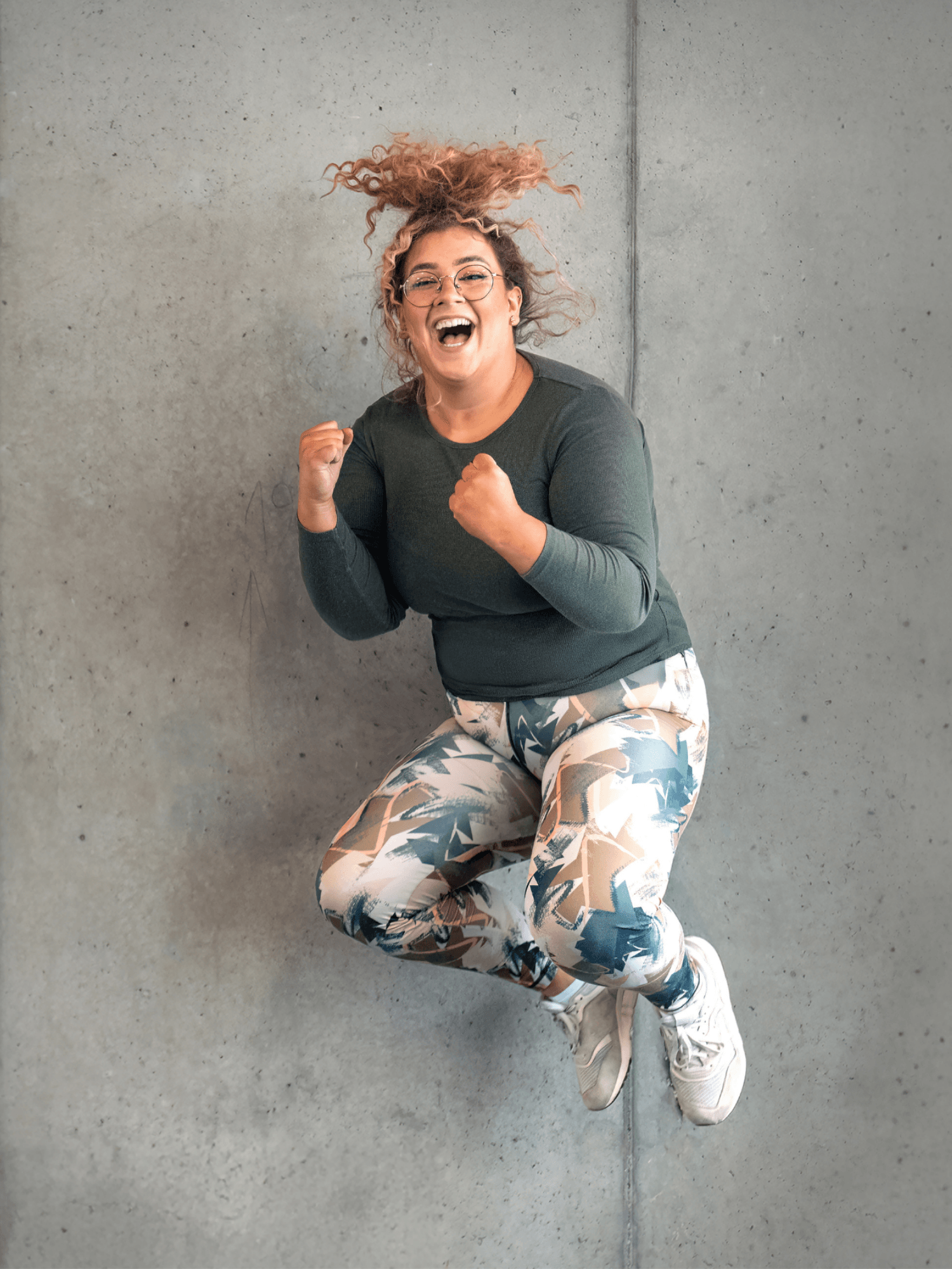 Ein fröhliches INJOY Mitglied springt in die Luft und lacht herzlich in die Kamera.