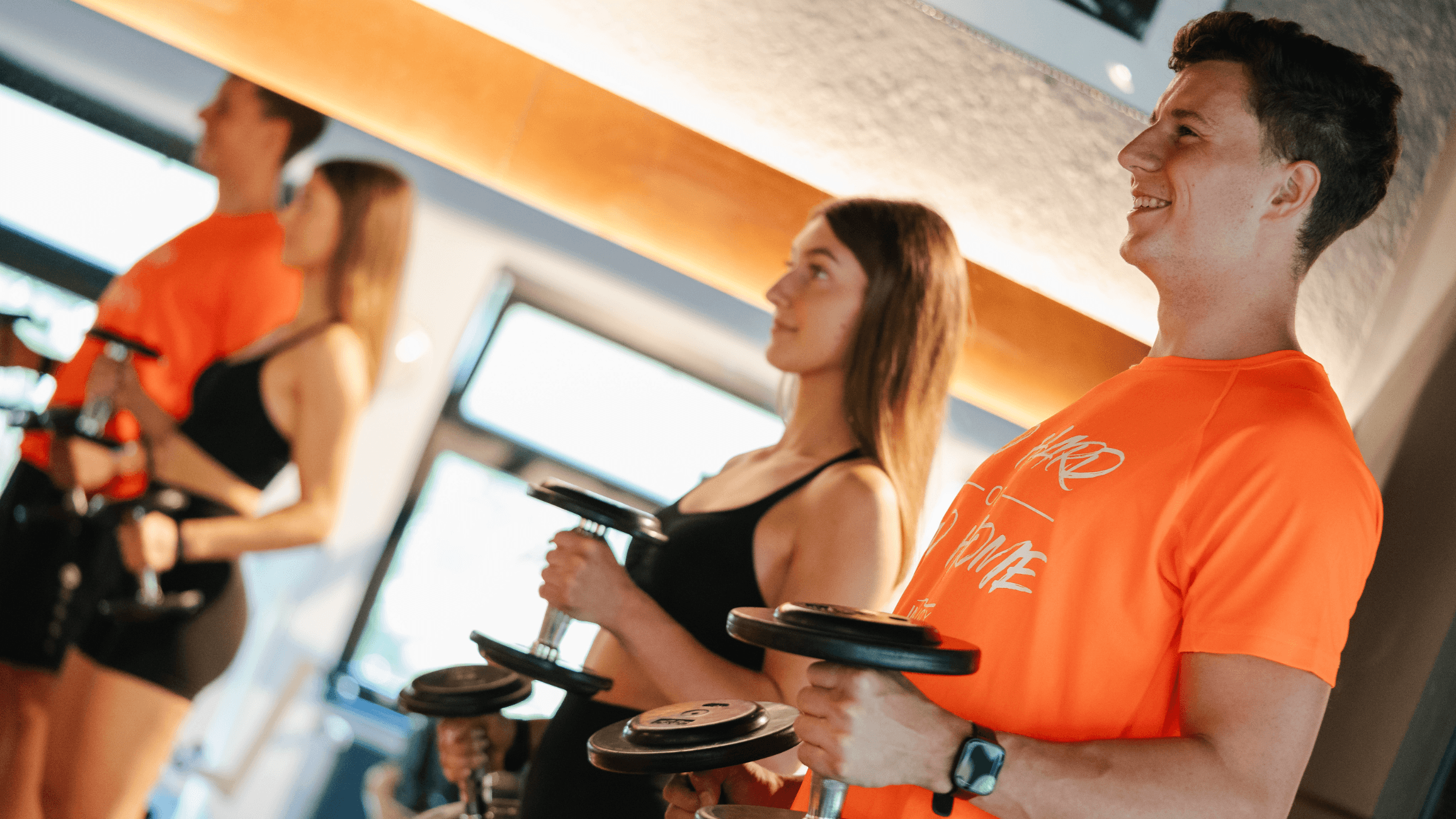Mann und Frau trainieren Trizeps mit einer Kurzhantel im INJOY Fitnessstudio Weida.