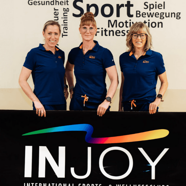 Die drei Franchisenehmerinnen des INJOY Papenburg posieren vor einem INJOY Banner.