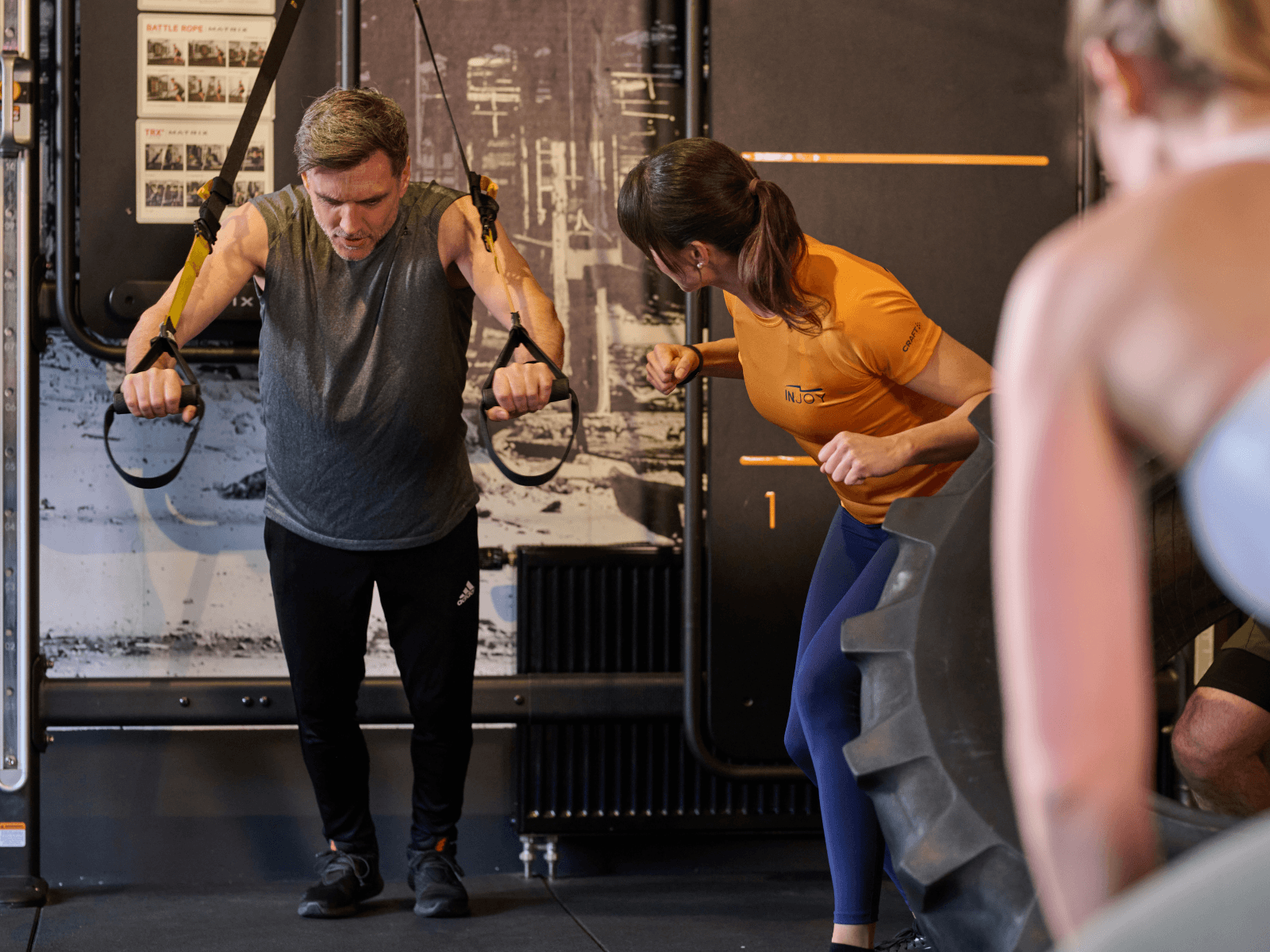 Ein Gruppe von Firmenfitnessteilnehmern trainiert gemeinsam mit einer INJOY Trainerin im Fitnessstudio.