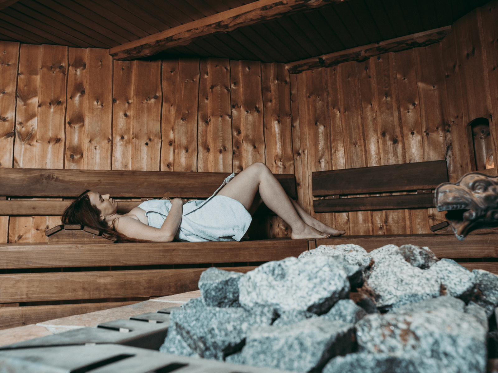 Ein weibliches Mitglied des INJOY Fitnessstudios in Syrau entspannt in der Sauna.