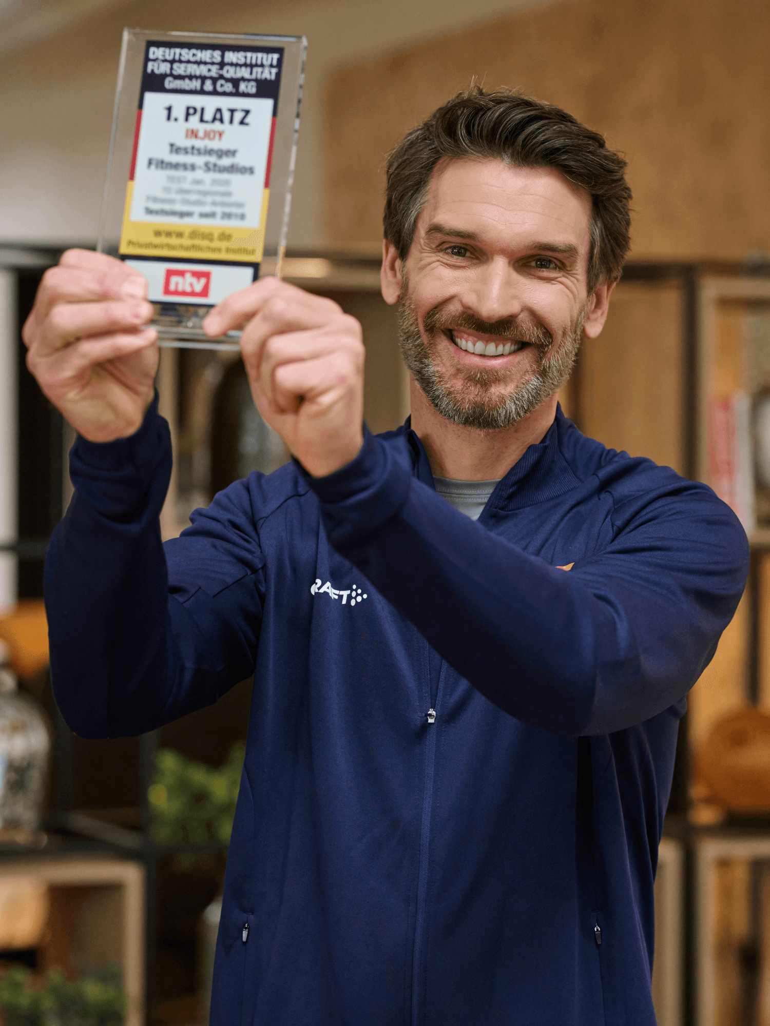 Ein stolzer INJOY Trainer präsentiert die Auszeichnung zum 1. Platz für Service und Beratung.