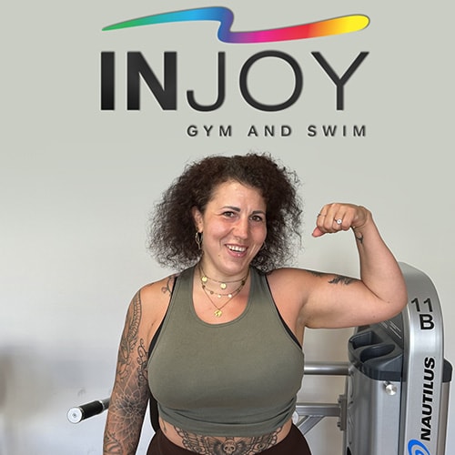 Ein glückliches INJOY Gym and Swim Mitglied posiert mit angespanntem Bizeps.