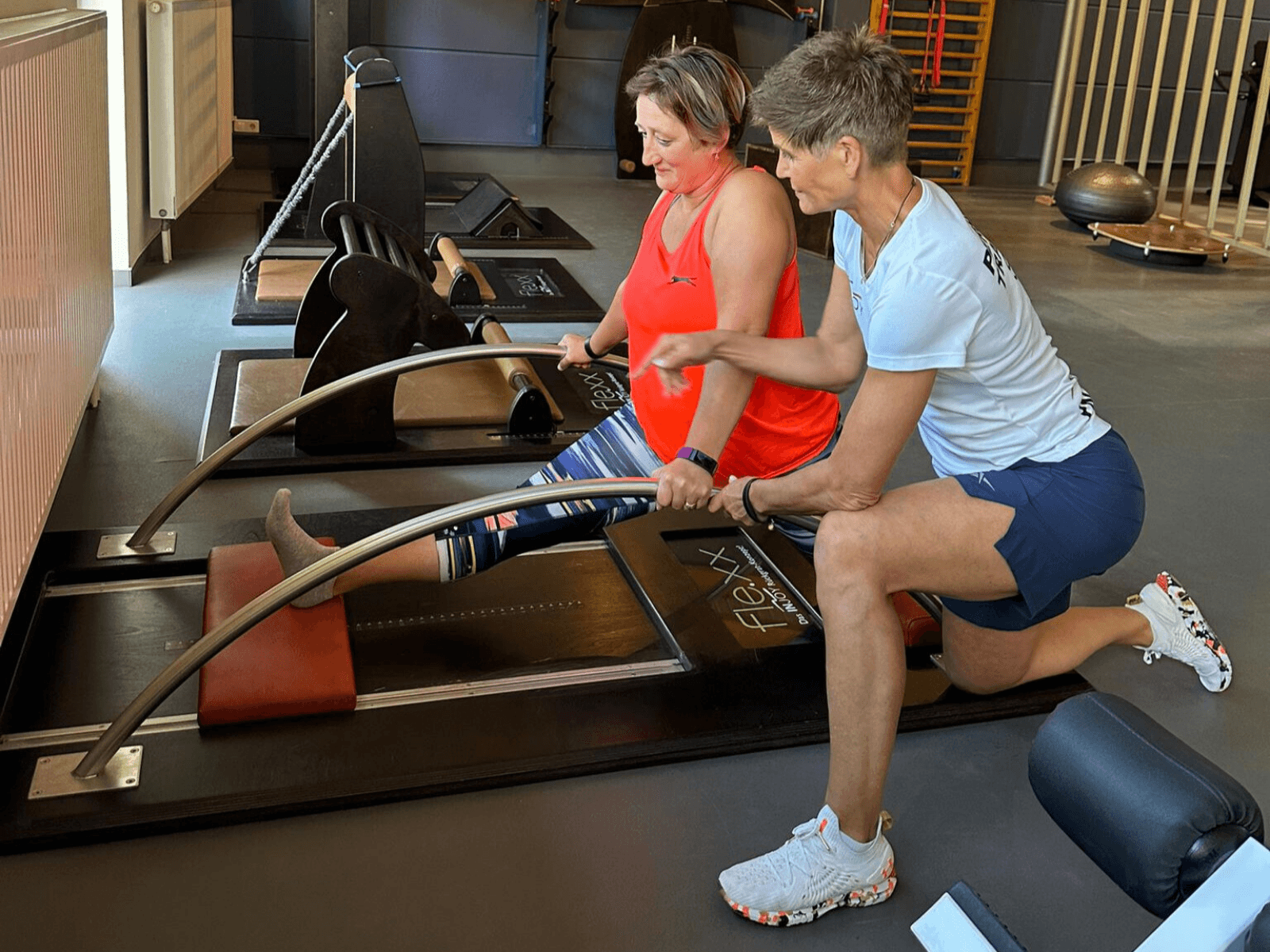 Ein Trainer zeigt einer Frau eine Strech-Übung ein einem Flexx Dehnungsgerät im INJOY Fitnessstudio Rudolstadt