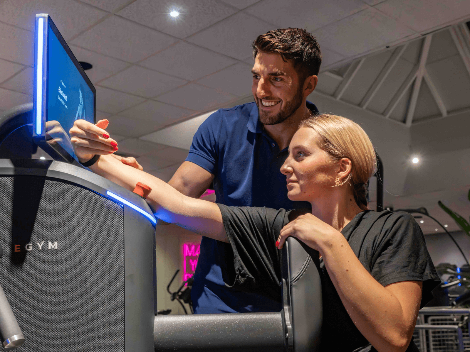 Ein INJOY Trainer betreut ein Mitglied an einem EGYM Gerät im INJOY Fitnessstudio Kempten.