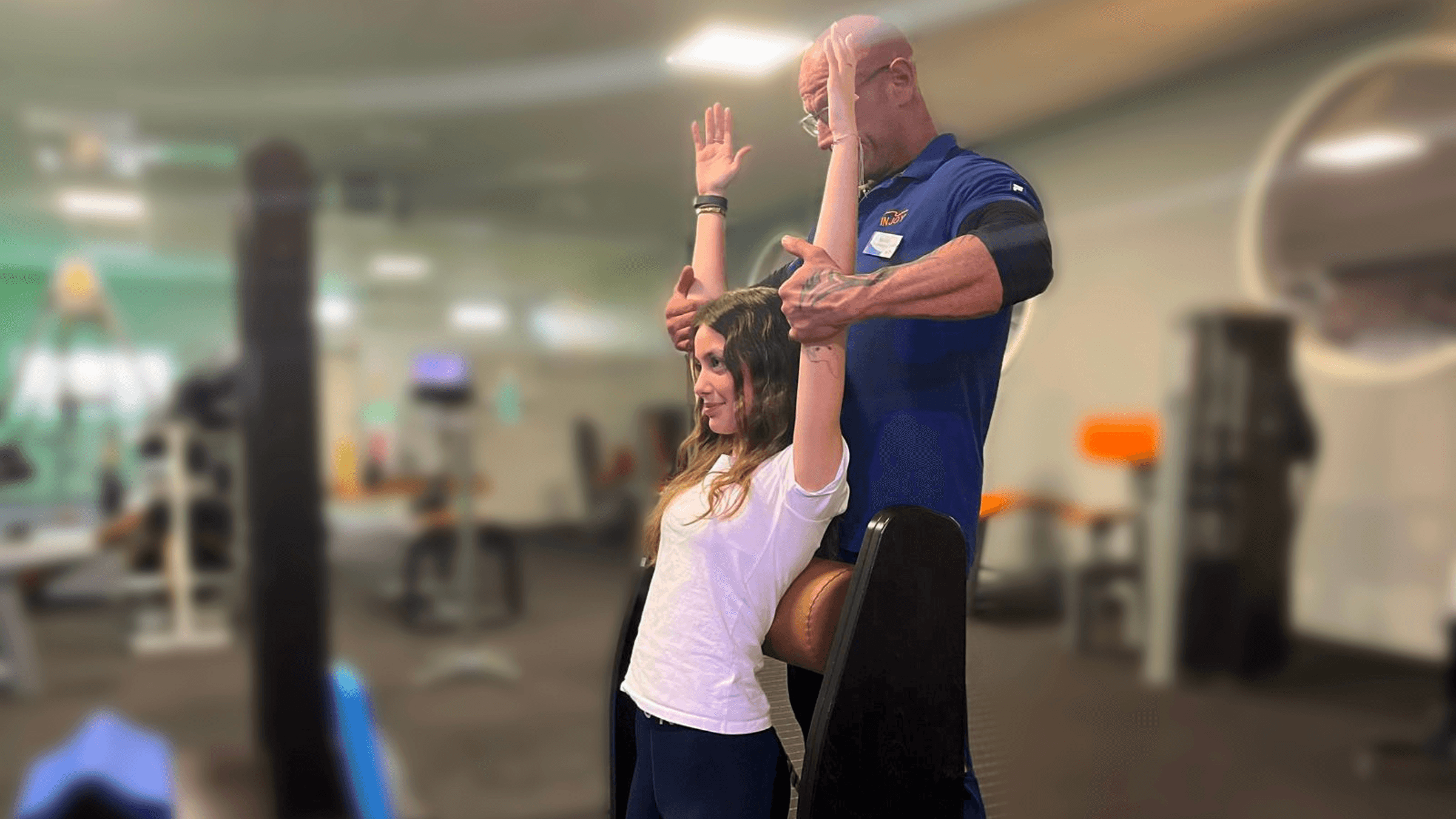 Ein INJOY Trainer des INJOY Fitnessstudio in Neuötting korrigiert die Form eines Mitglieds bei einer Beweglichkeitsübung.