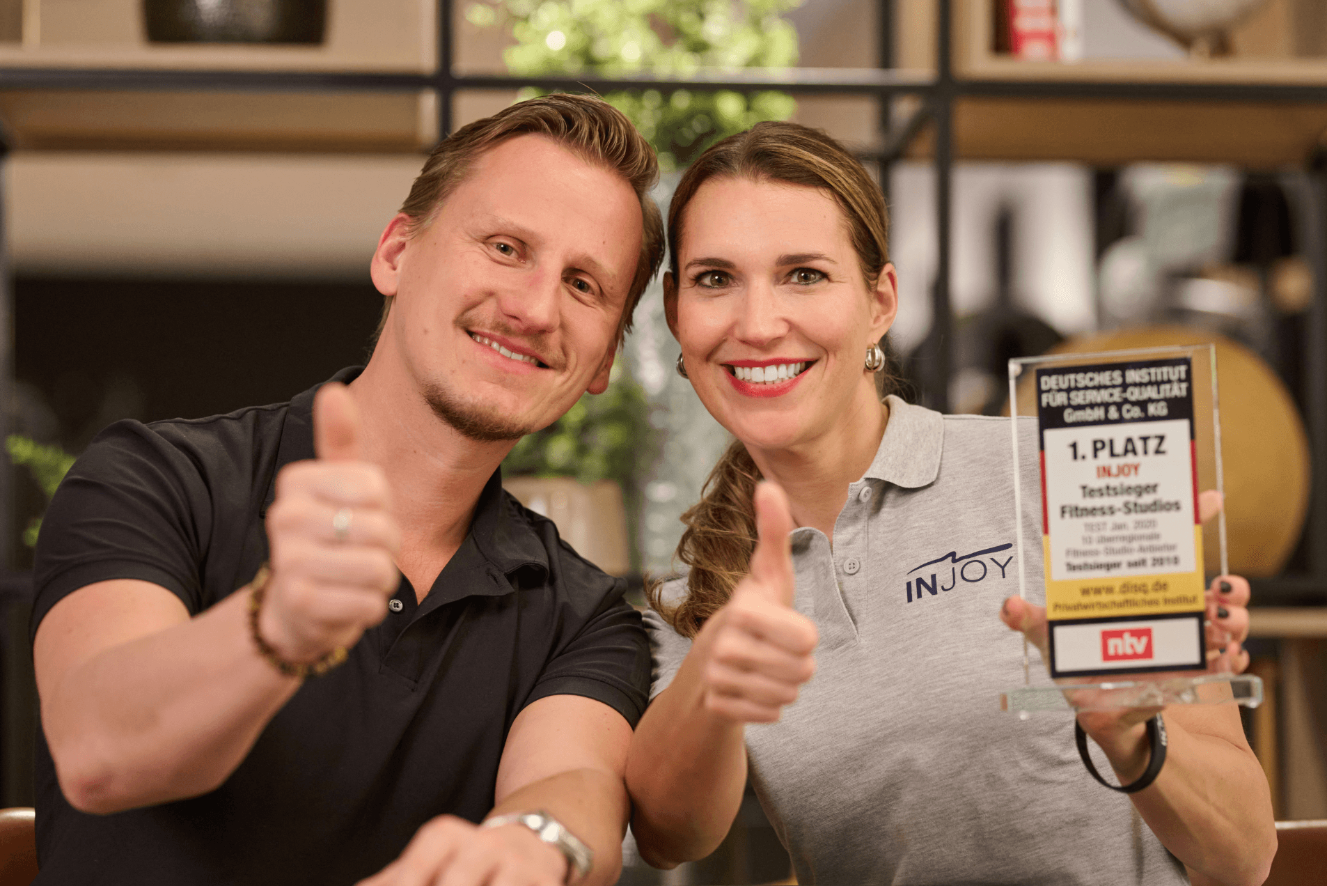 Eine INJOY Beraterin und ein INJOY Franchisenehmer zeigen beide einen Daumen hoch in die Kamera.