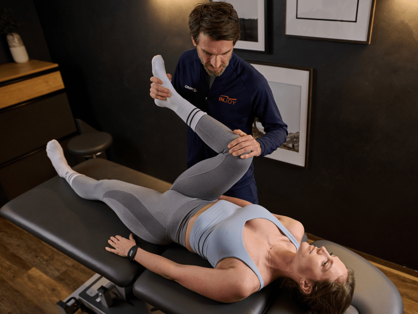 Ein attraktiver INJOY Physiotherapeut behandelt ein weibliches Mitglied.