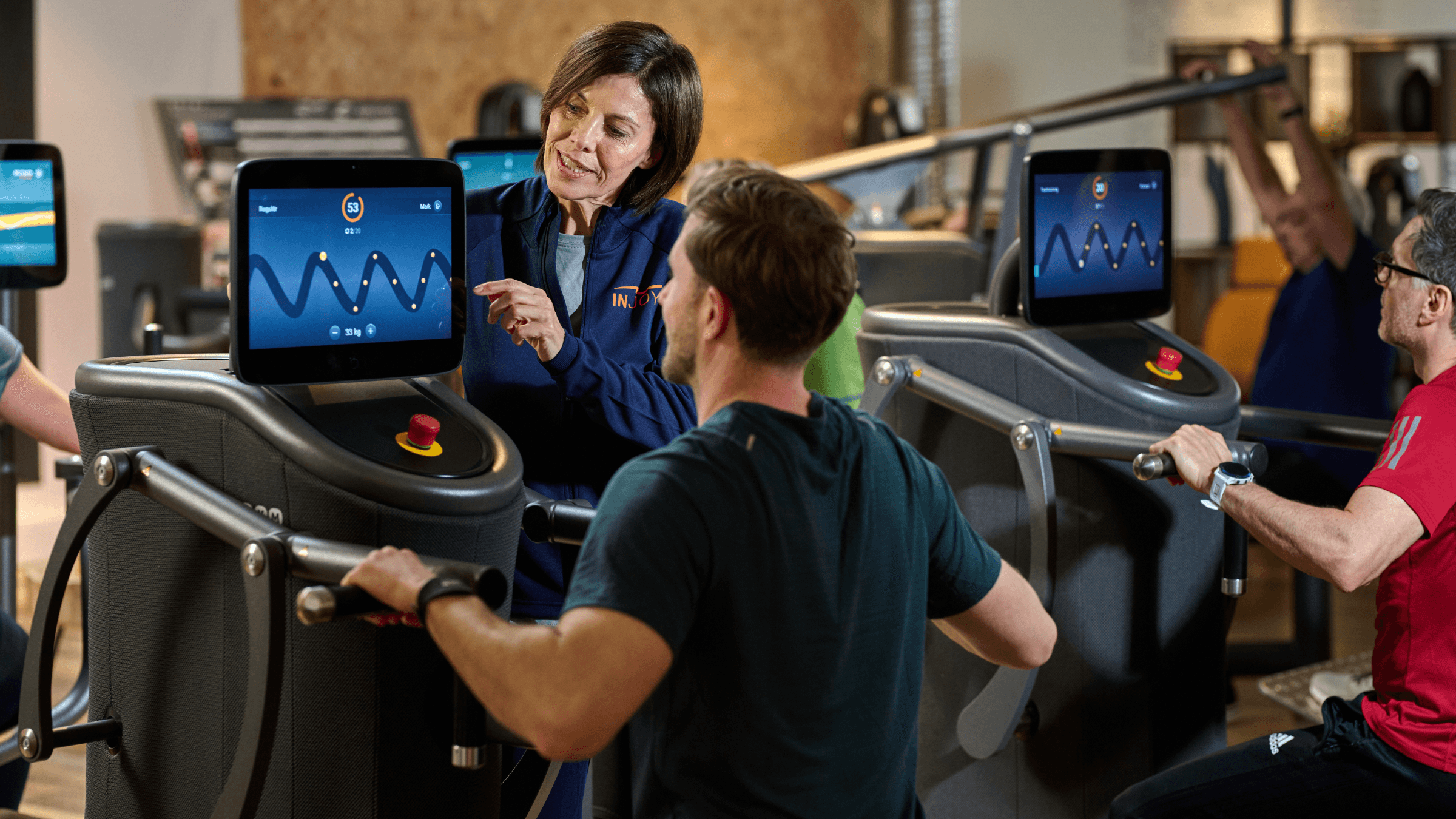 Eine INJOY Trainerin weist ein Mitglied in ein EGYM Gerät ein.