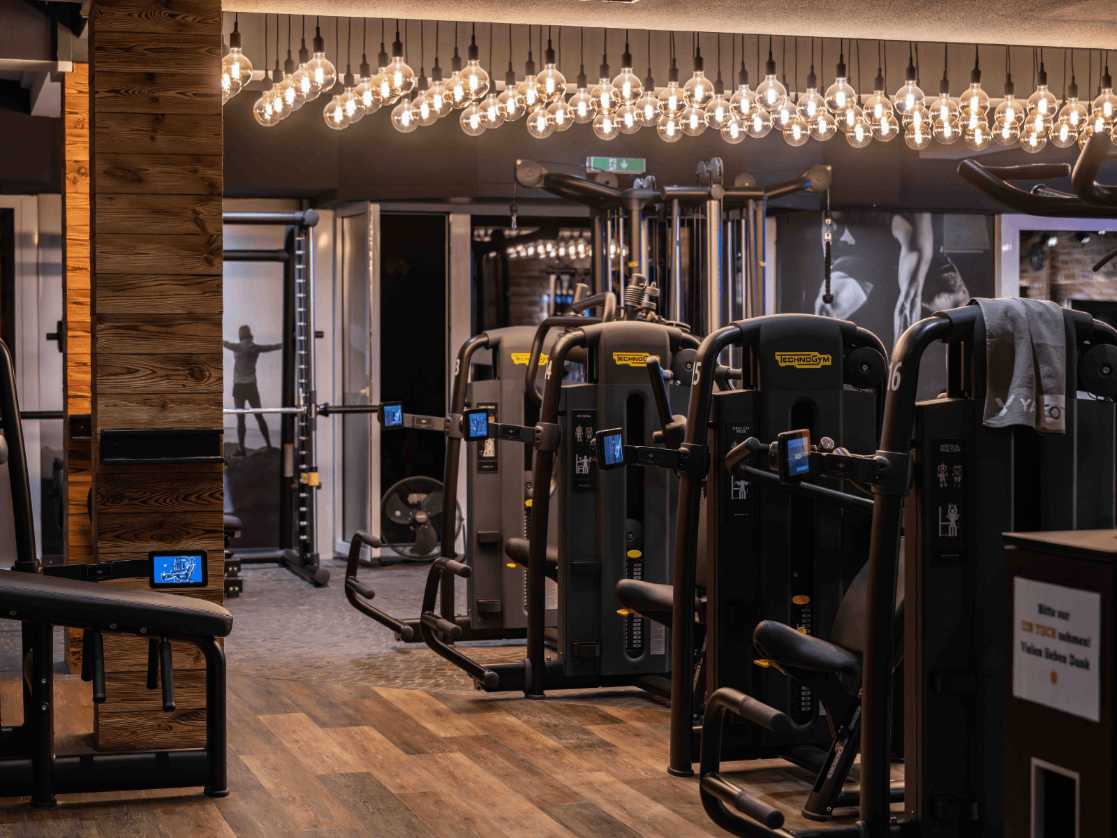 Eine Aufnahme des INJOY Fitnessstudios in Kempten. Im Vordergrund neue Technogym Geräte. Darüber eine warme Lichtinstallation.