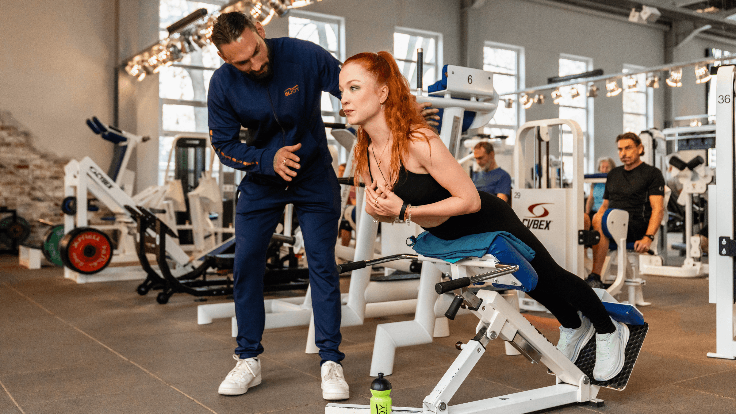 Ein INJOY Trainer des INJOY Fitnessstudios Berlin-Steglitz betreut ein Mitglied beim Rückenstrecker.