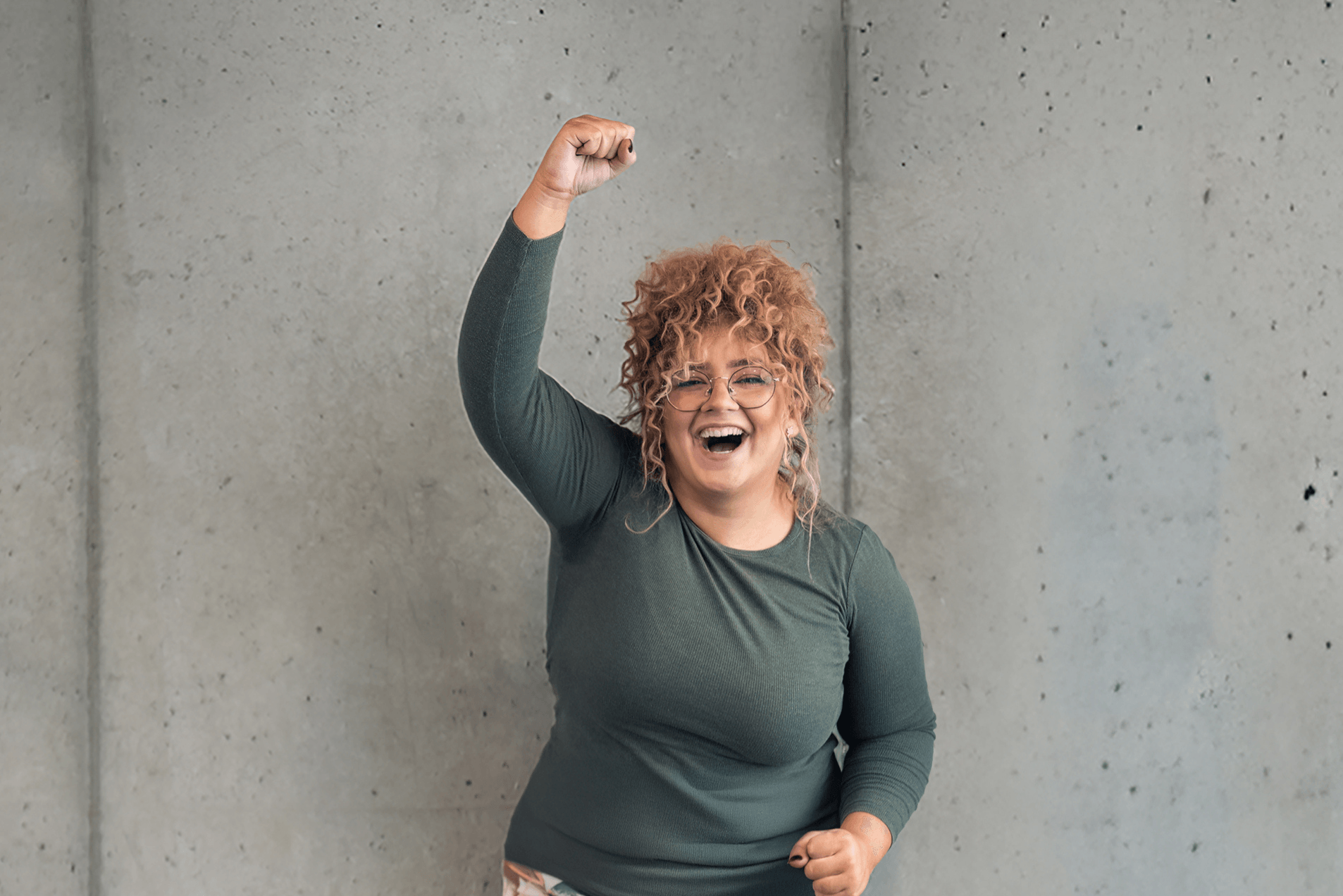 Ein glückliches INJOY Fitnessstudio-Mitglied streckt eine Fast nach oben und lächelt in die Kamera.