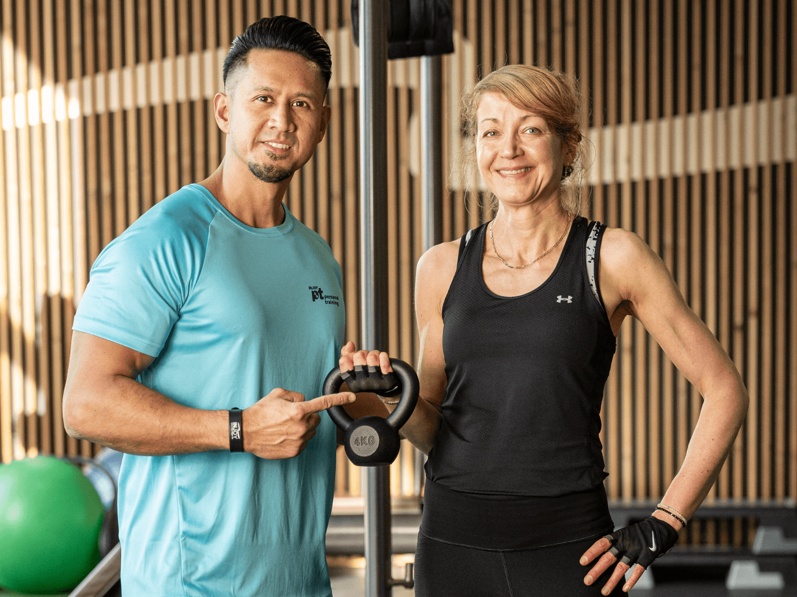 Ein Personal Trainer vom INJOY Fitnessstudio Hagen steht neben einem Mitglied. Gemeinsam posieren sie stolz für ein Foto.